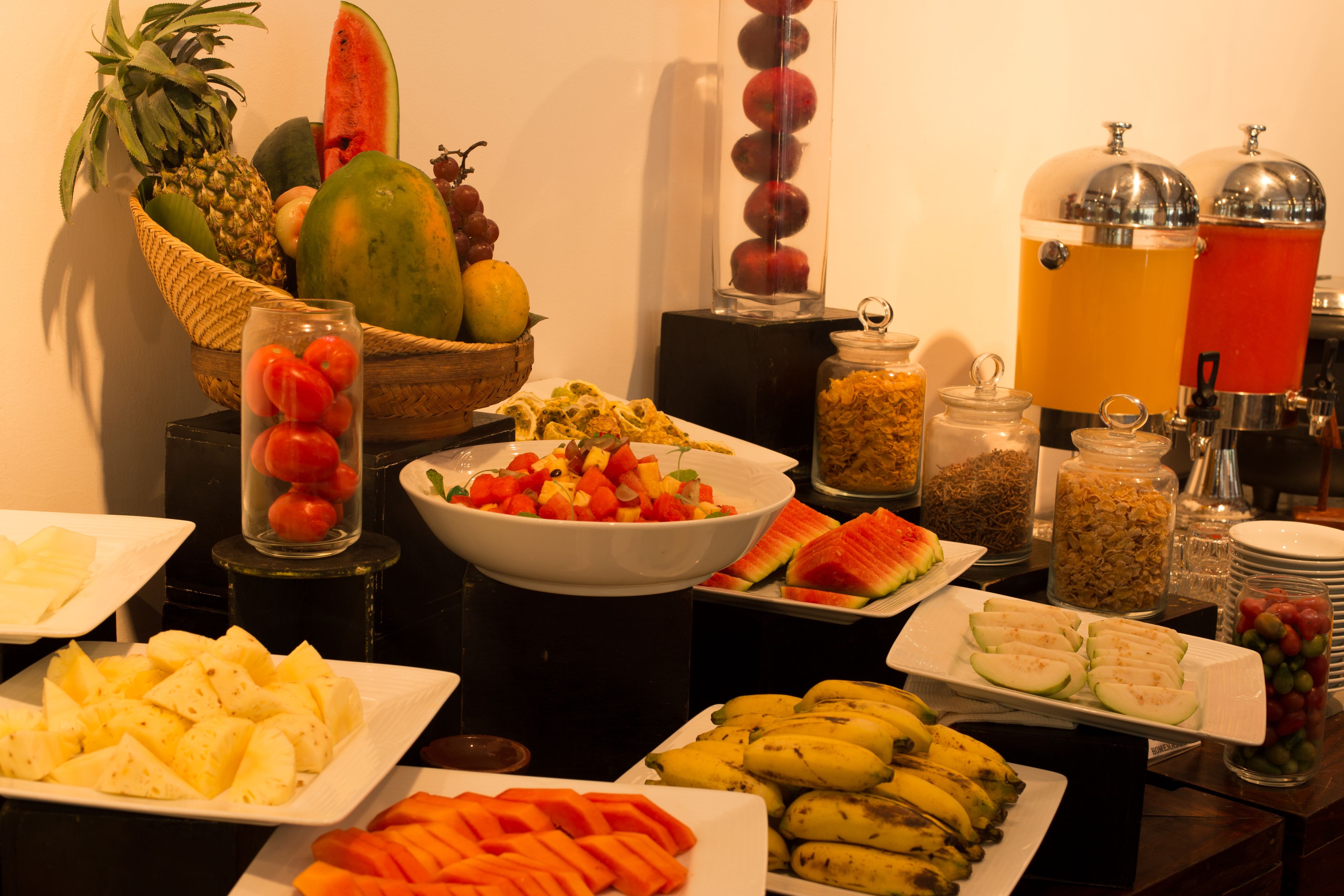 A buffet with various fruits, vegetables, and beverages.