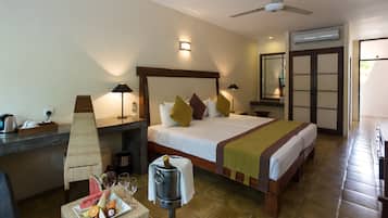 Habitación de hotel con cama, mesitas de noche, escritorio, silla, minibar y carrito para el minibar.