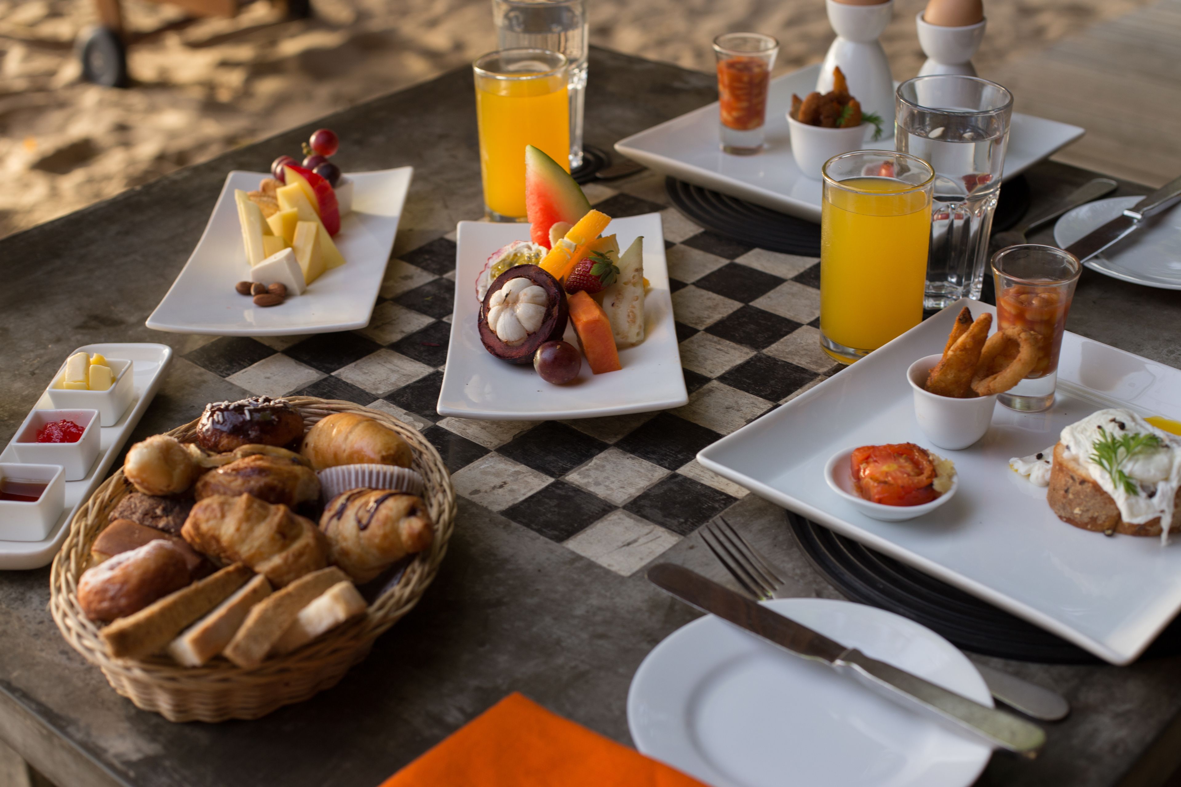 A checkered table with breakfast items including bread, fruit, and beverages.