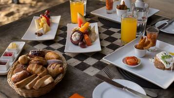 A checkered table with breakfast items including bread, fruit, and beverages.