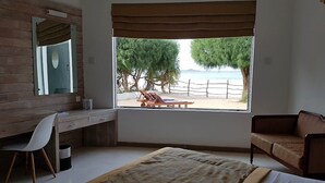Une chambre avec une grande fenêtre, un bureau, une chaise, un lit et un canapé.