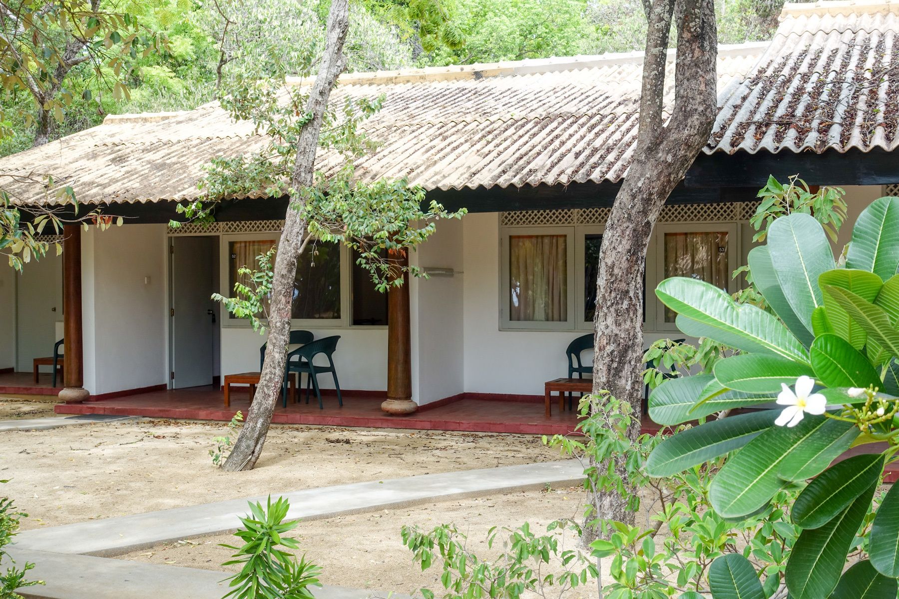 A traditional building with a tiled roof, wooden pillars, and a covered porch with chairs.