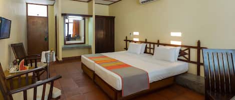 Une chambre d’hôtel comprenant un lit, un bureau avec une chaise, une fenêtre et un appareil de climatisation.