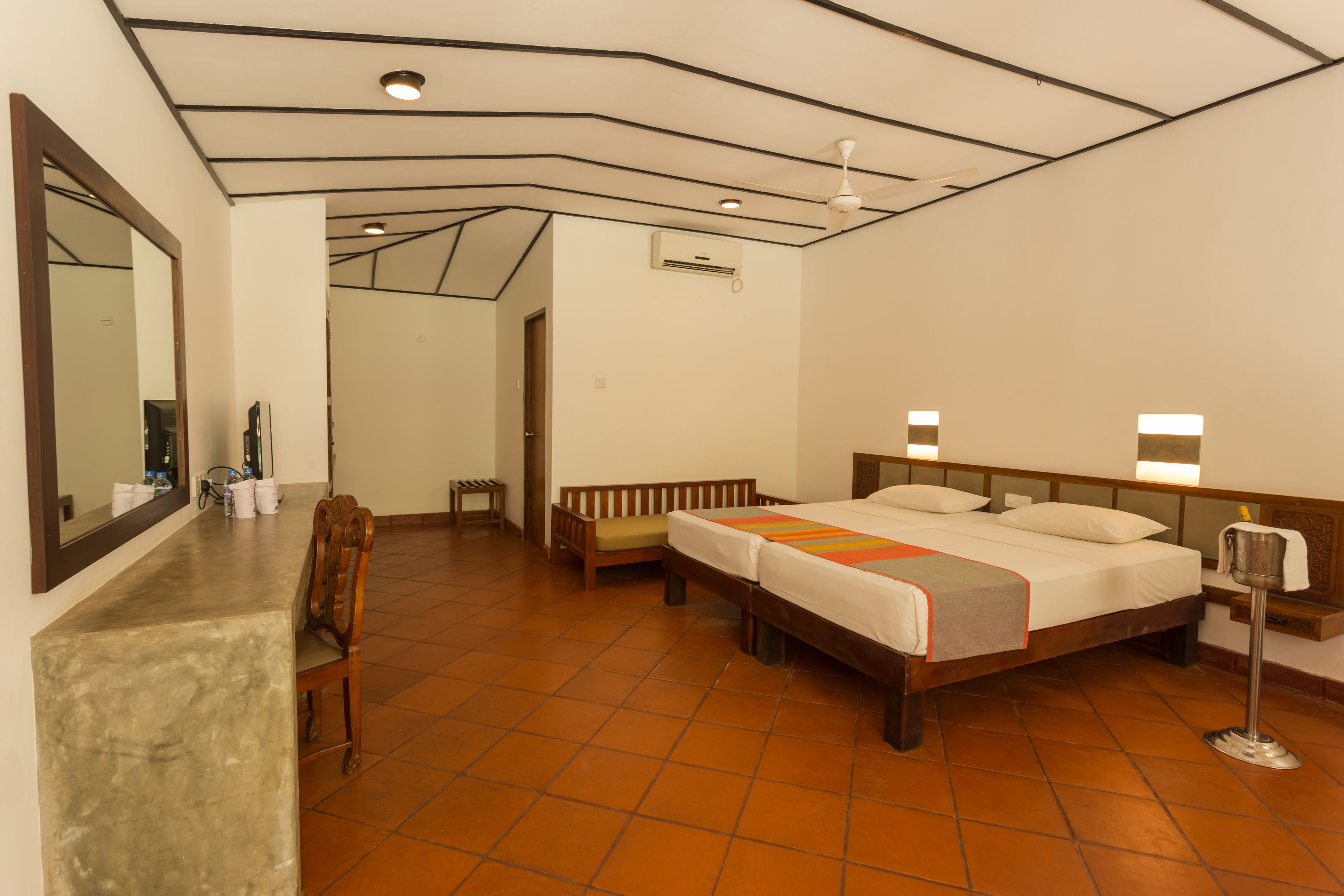A hotel room with a bed, a desk, a chair, a mirror, and a bathroom.