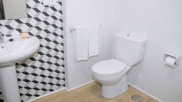 A bathroom with a white sink, toilet, and a geometric patterned wall.