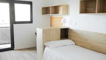 Un dormitorio con cama, escritorio y ventana.