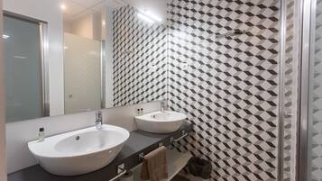 A modern bathroom with two sinks, a large mirror, and a patterned wall.