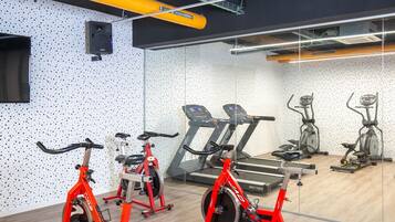 Une salle de sport équipée de vélos d’appartement, de tapis de course et d’appareils elliptiques.