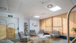 A modern waiting area with comfortable seating, a bookshelf, and a visible emergency exit sign.
