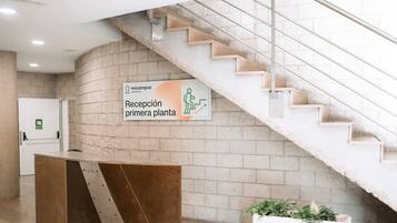 A reception area with a staircase, a reception desk, and a planter with plants.
