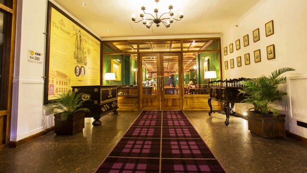 A hotel lobby with a checkered carpet, wooden doors, and framed pictures on the walls. - The Steuart by Citrus (Colombo)