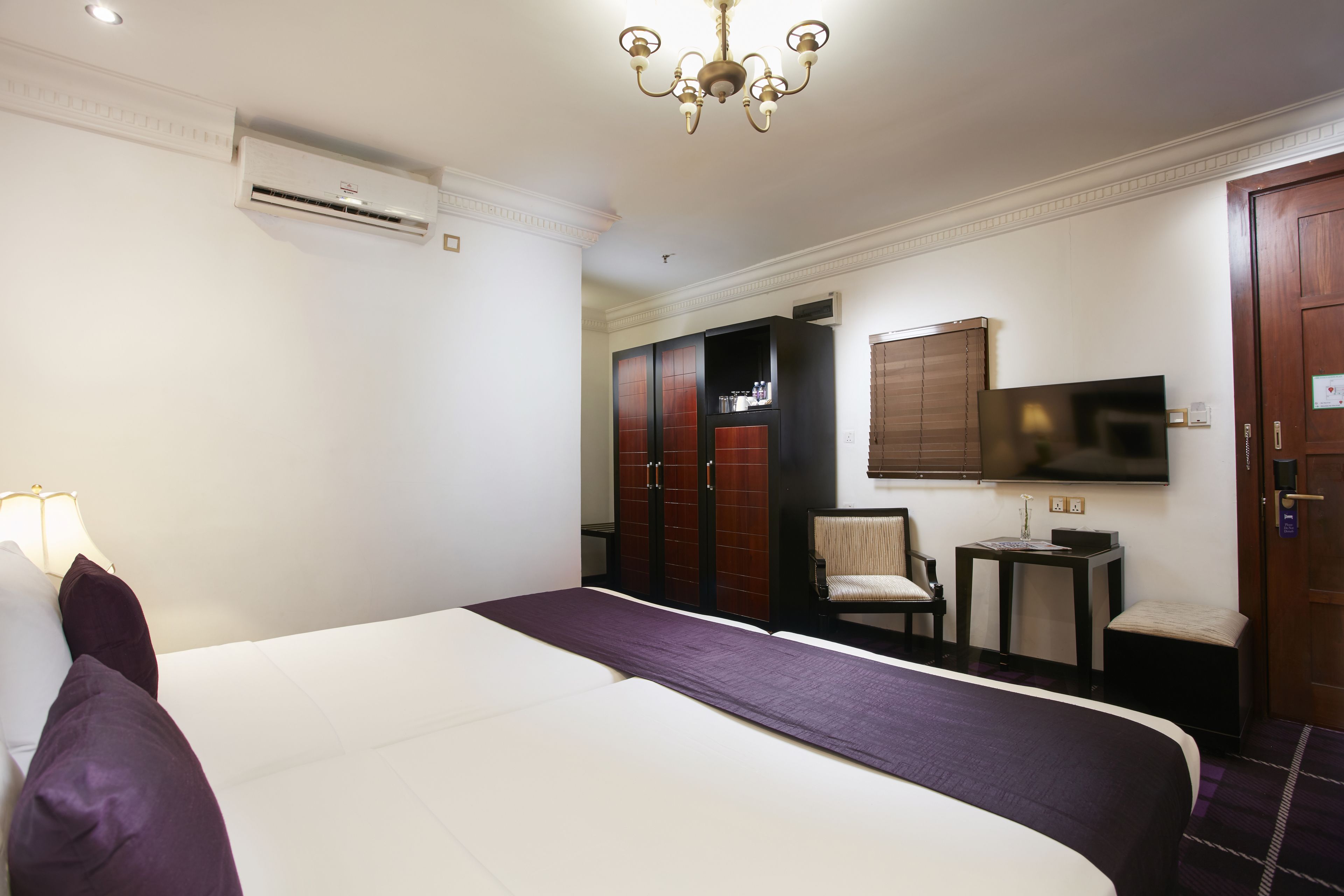 A hotel room with a large bed, a TV, a desk, and a wardrobe.