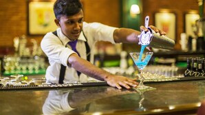 A bartender pouring a blue drink into a martini glass at a bar. - The Steuart by Citrus (Colombo)