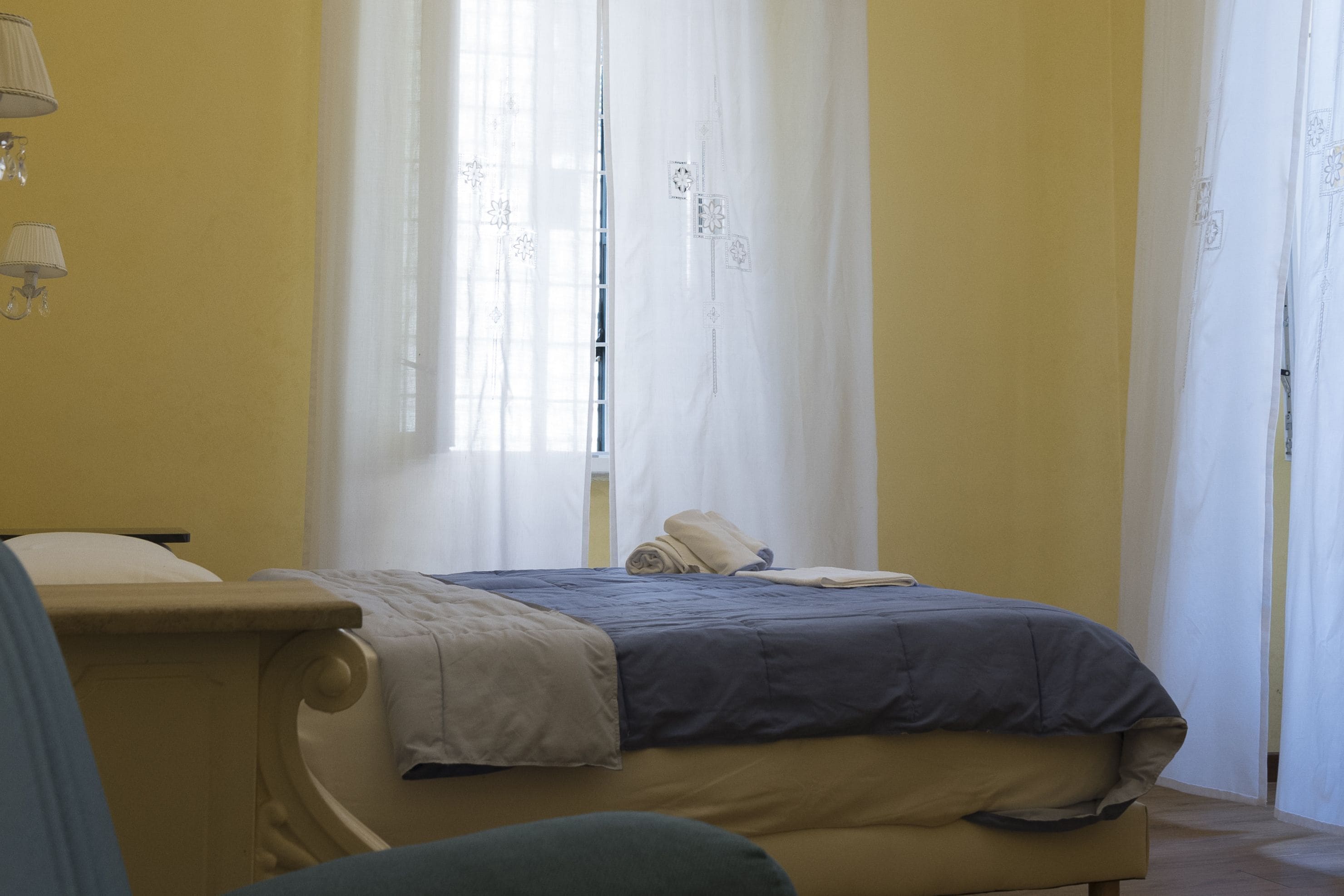 Une chambre à coucher avec un lit, une chaise et une fenêtre avec des rideaux.