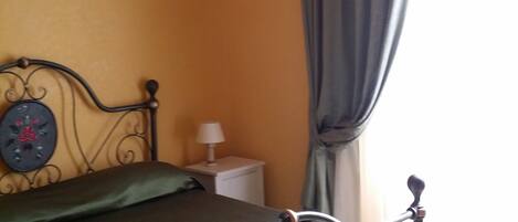 A room with a bed, a nightstand, a lamp, and a wall-mounted air conditioner.