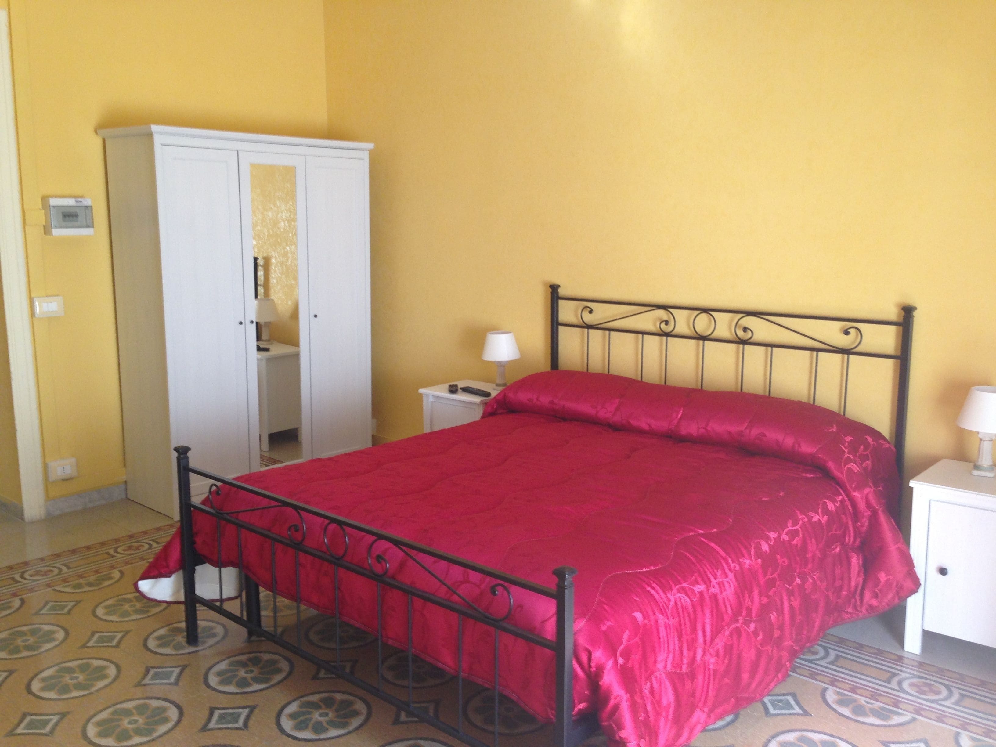 Une chambre à coucher avec un lit, une armoire, une table de chevet et une lampe.