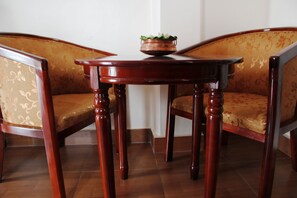 Un rincón con una zona de estar, dos sillas de madera y una mesita con un cuenco decorativo.