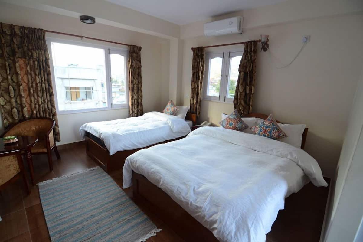 A hotel room with two beds, a desk, and a chair.