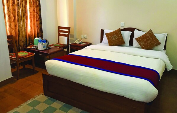 Una habitación de hotel con una cama, un escritorio con teléfono y una silla.