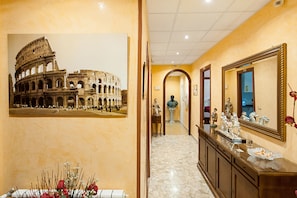 A hallway with a large photo of the Colosseum, a marble floor, a mirror, and a statue.