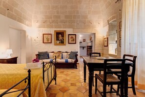 Une pièce confortable avec un lit, une table en bois avec des chaises, un canapé avec des coussins et un coin repas.