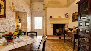 A dining area with a stone wall, a fireplace, and a wooden cabinet with drawers.