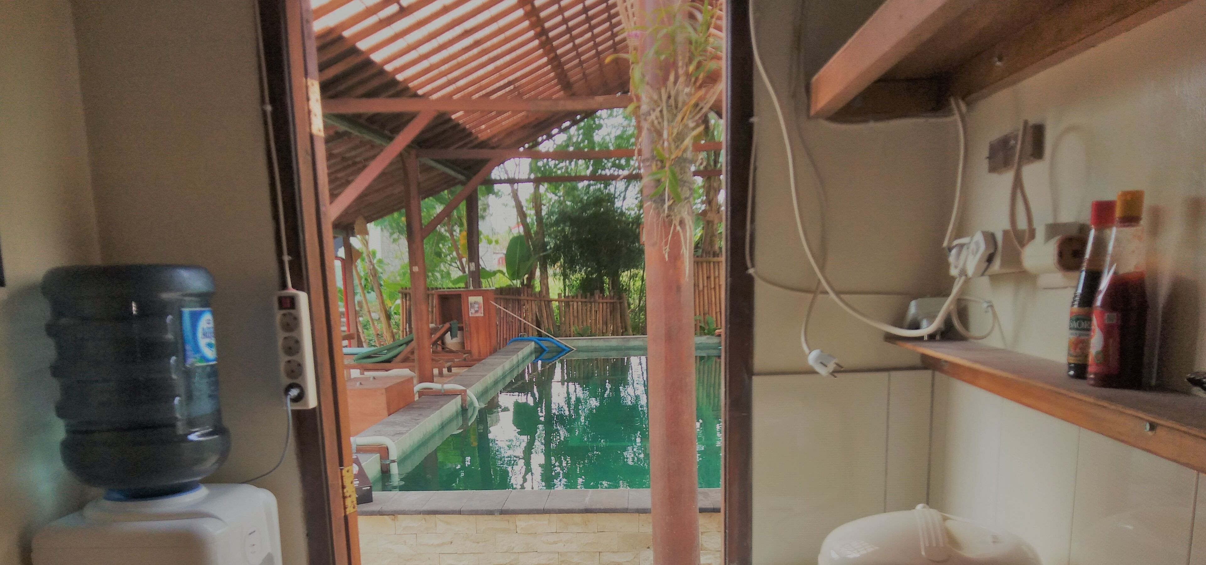 Habitación con vista a una piscina, dispensador de agua, teléfono y estante con artículos de aseo.