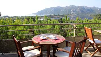A wooden table with chairs and a view of a lake and mountains.