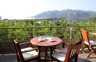 Una mesa de madera con sillas y vistas a un lago y montañas.