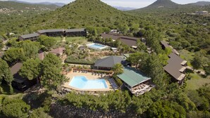 Un resort con varias construcciones, una amplia piscina central y zonas verdes circundantes.