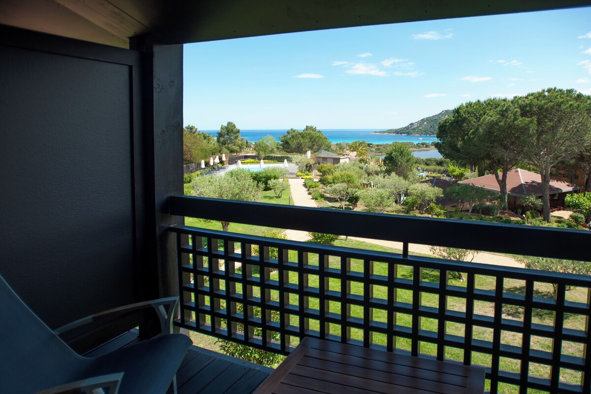 A balcony with a view of a landscaped garden and a body of water.