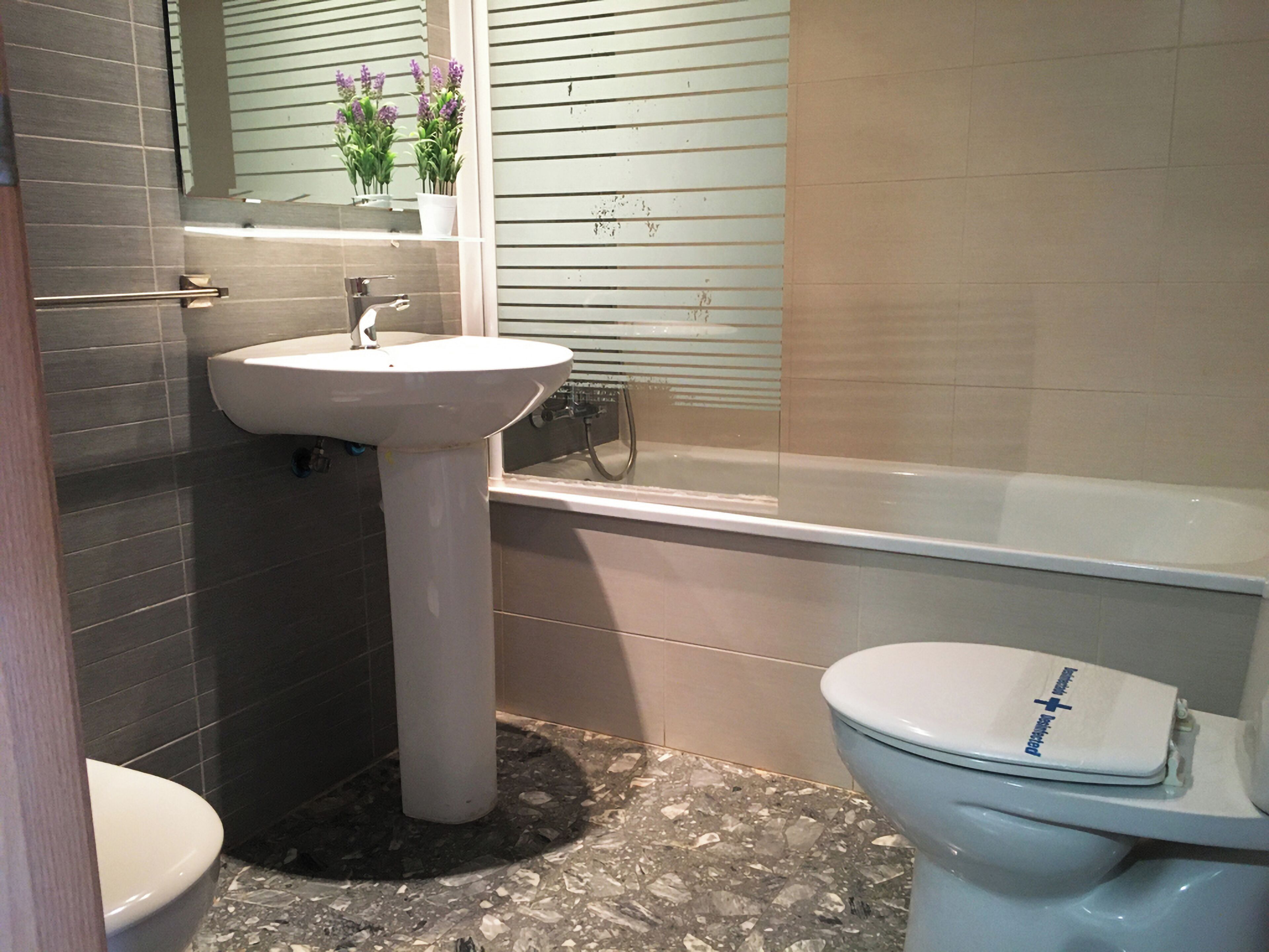 Un baño con lavamanos pedestal, inodoro y bañera.