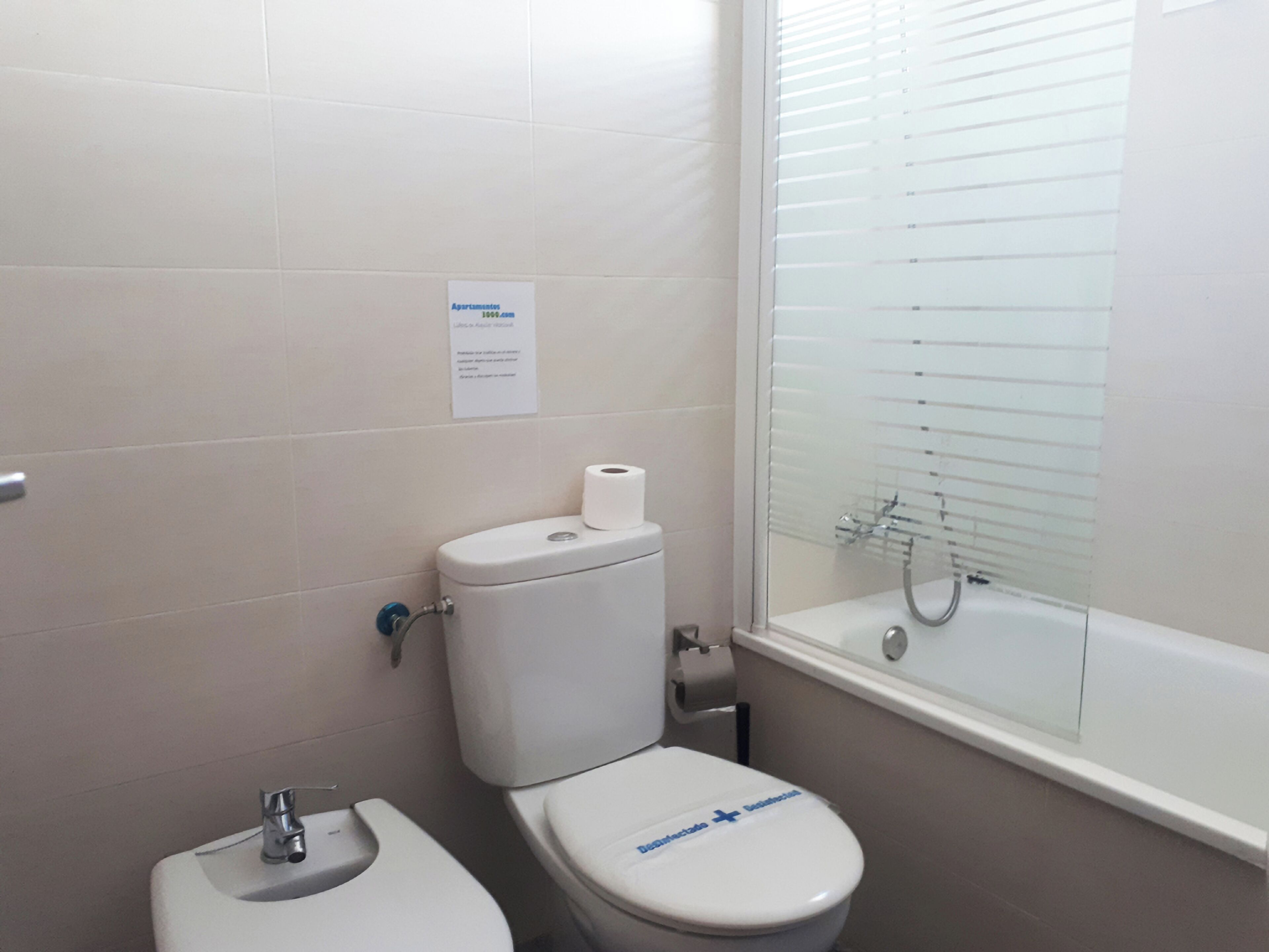A bathroom with a toilet, sink, and a glass-enclosed shower.