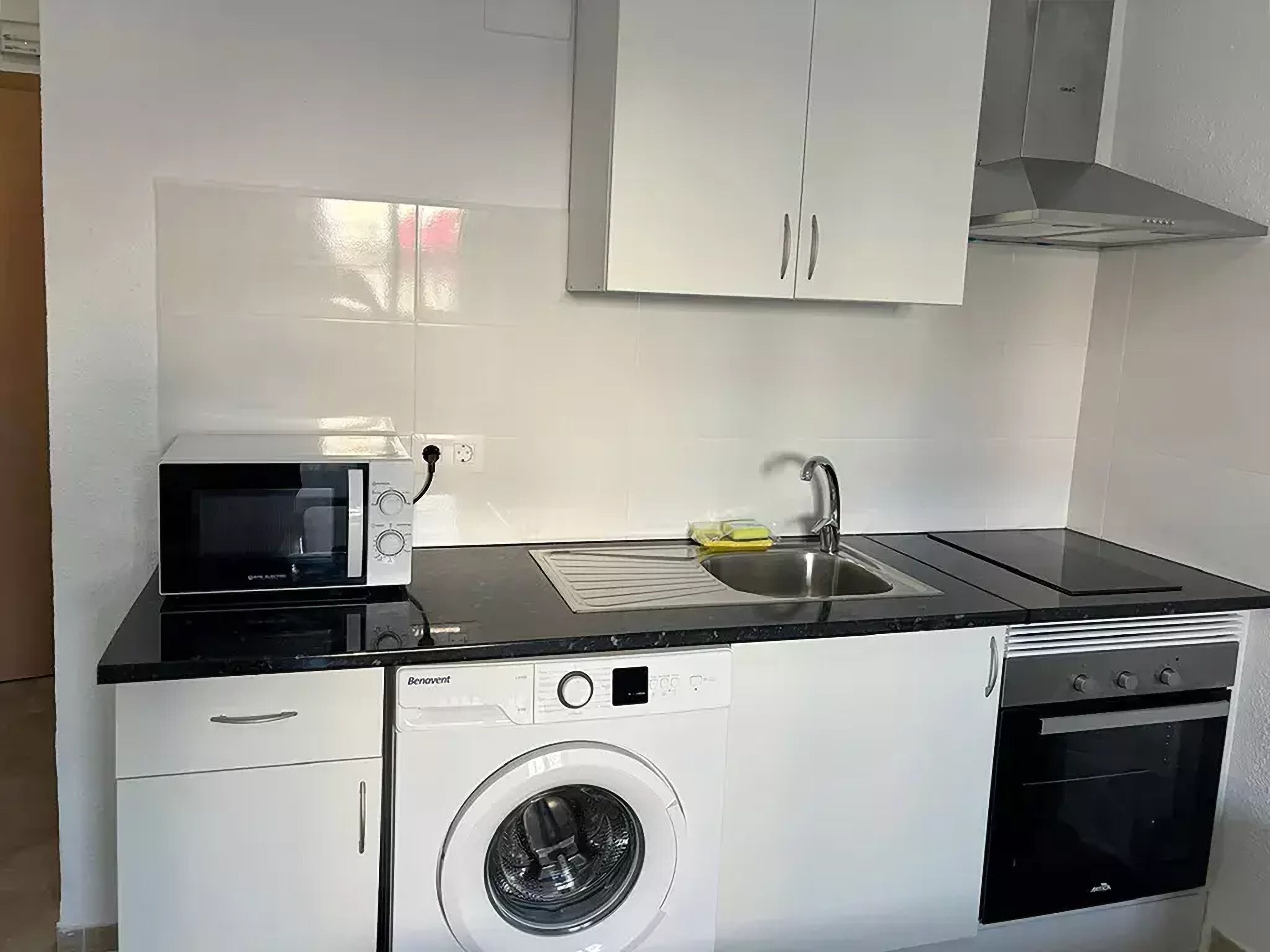 Cocina compacta con microondas, fregadero, lavadora y horno.
