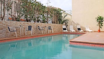 Relax by the pool surrounded by lush greenery and comfortable lounge chairs.