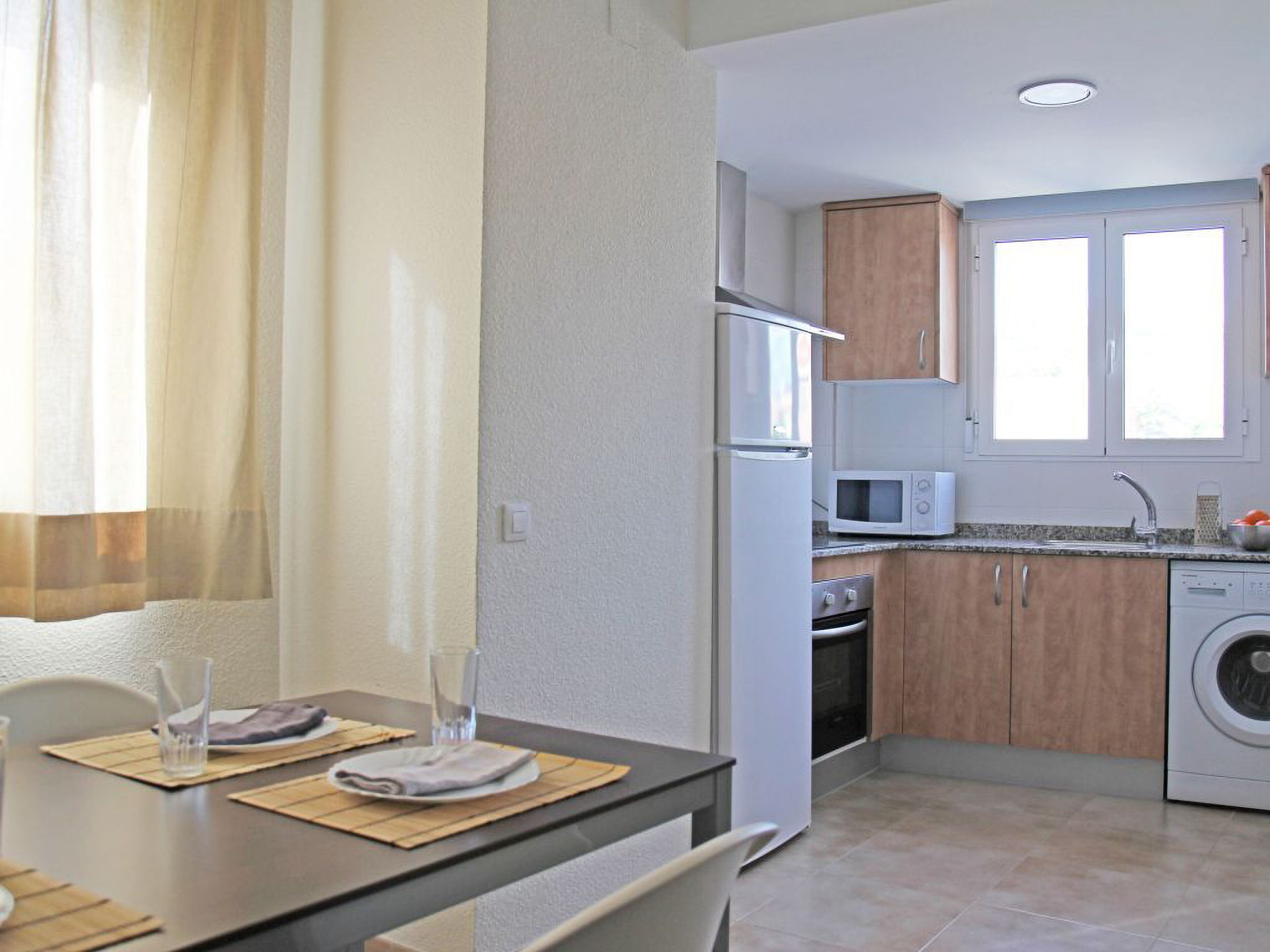Una cocina compacta equipada con refrigerador, microondas, horno y lavadora.
