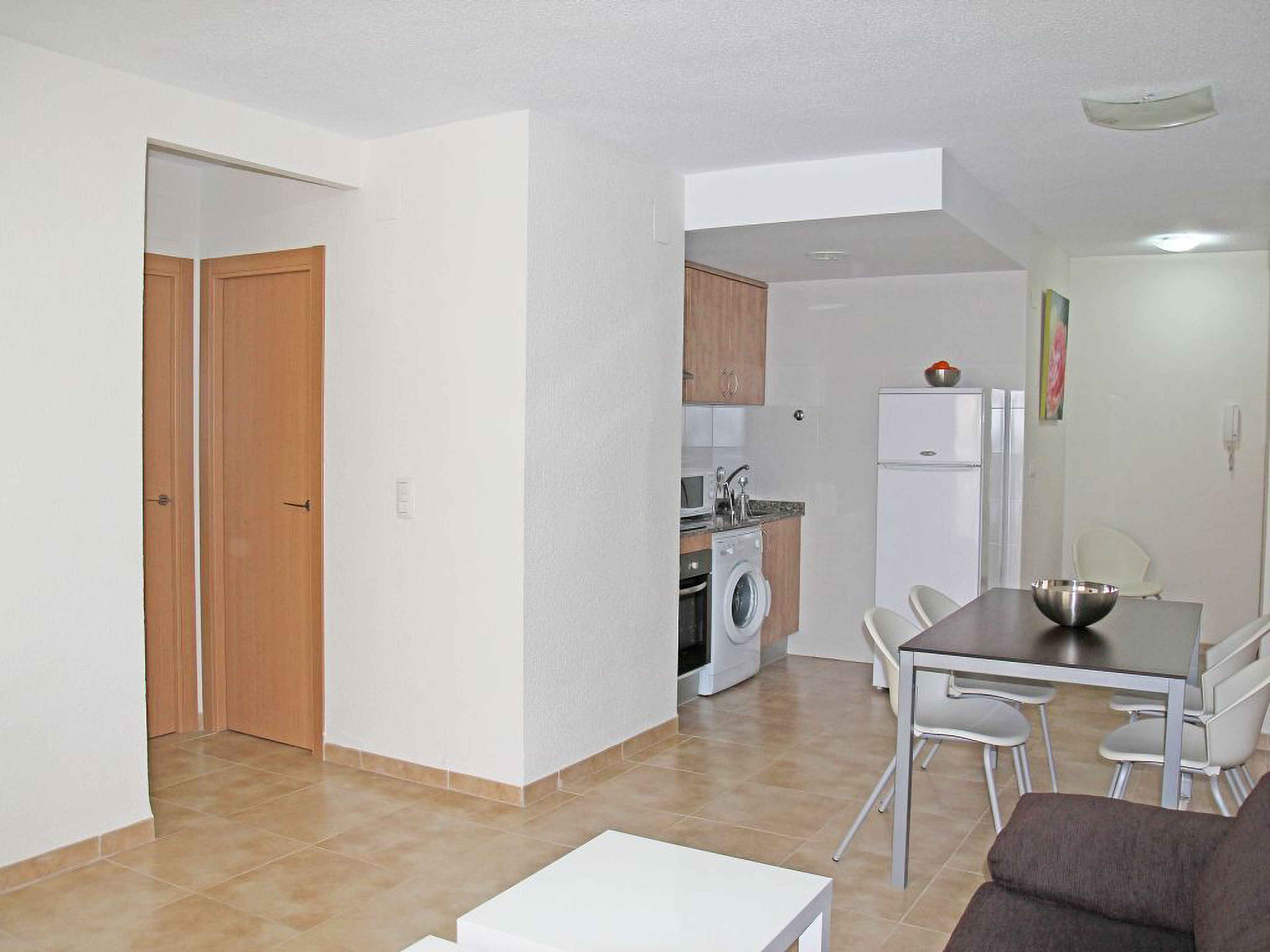 A compact living space with a dining area, kitchenette, and a separate entrance door.