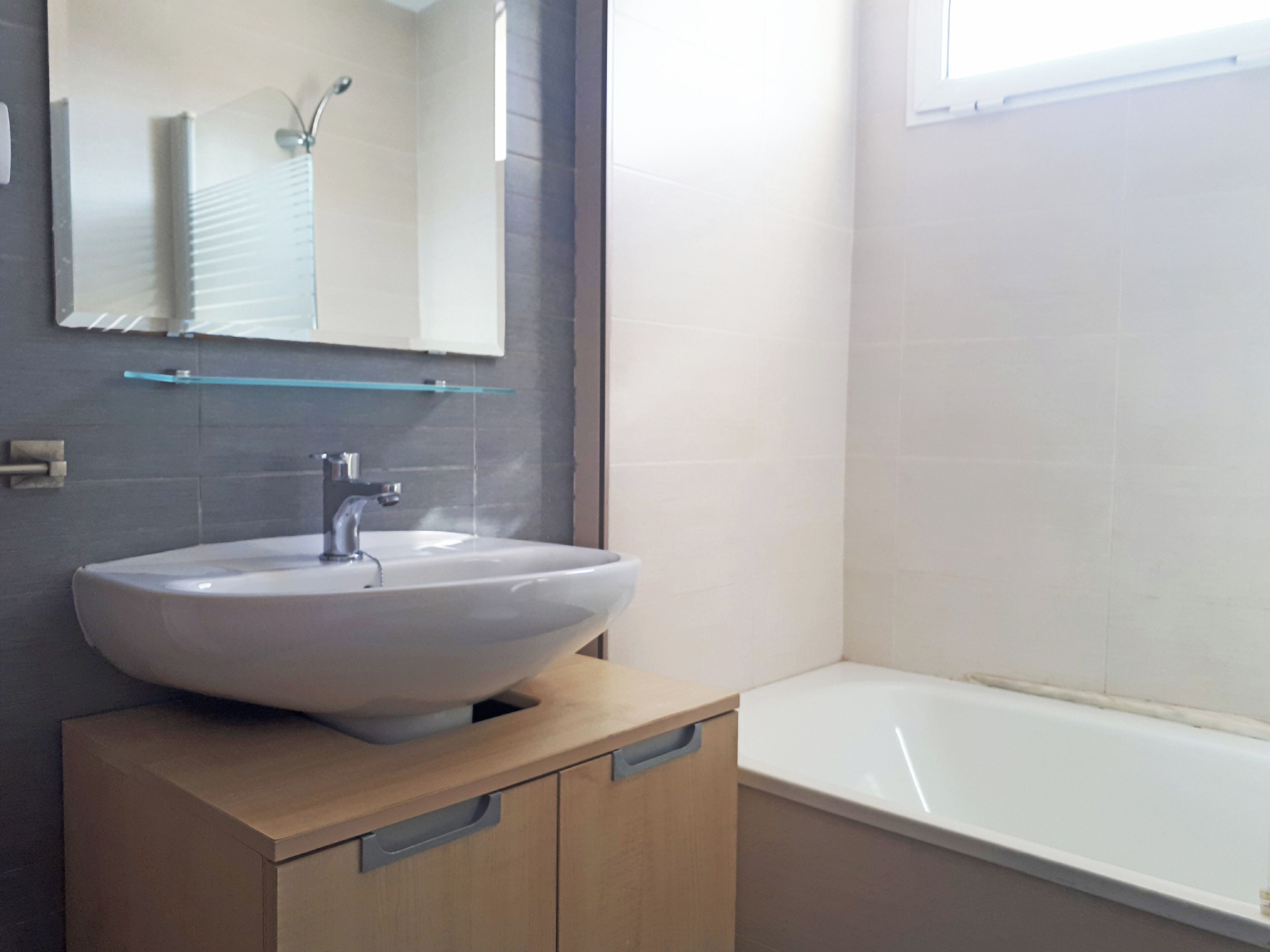 Un baño con lavamanos blanco, espejo y bañera.