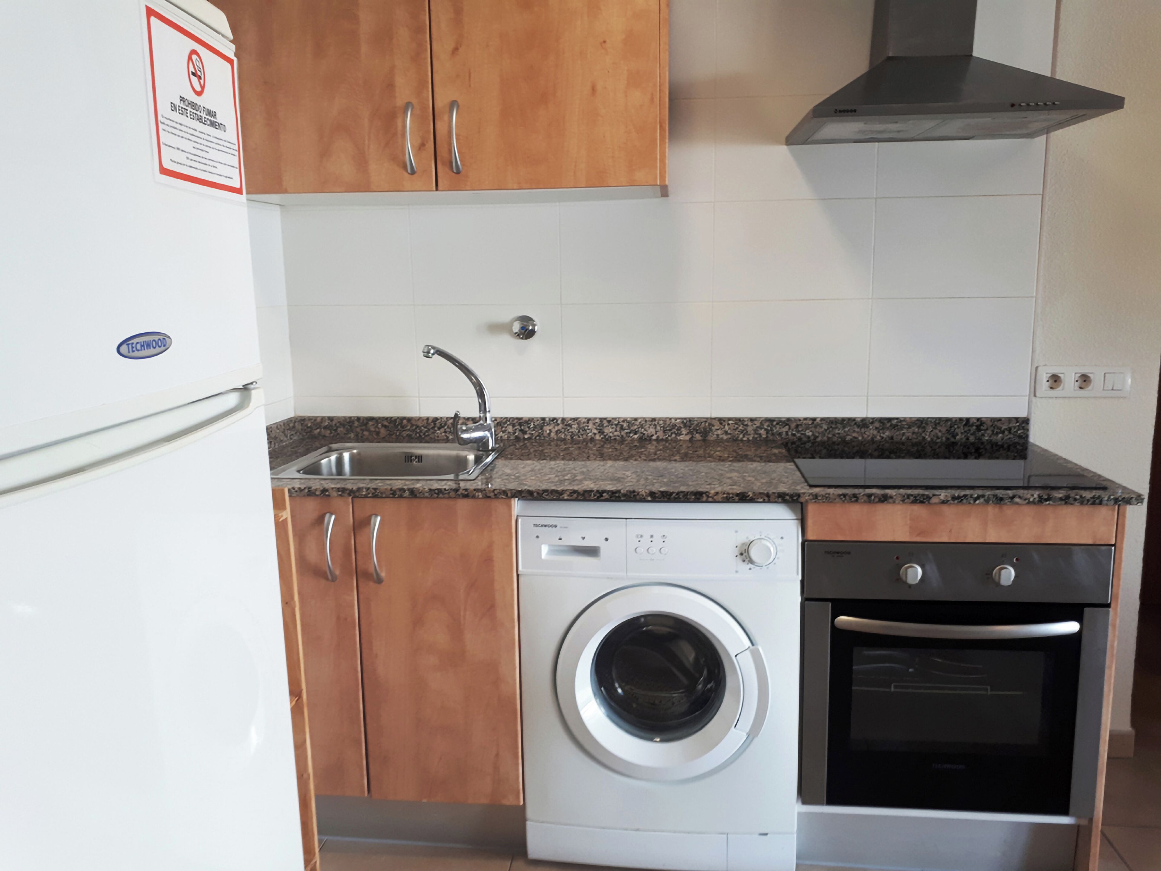 Een keuken met een wasmachine, oven en spoelbak.