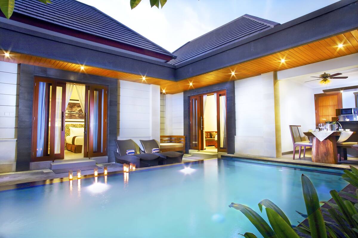 A modern poolside area with a pool, lounge chairs, and a dining area.