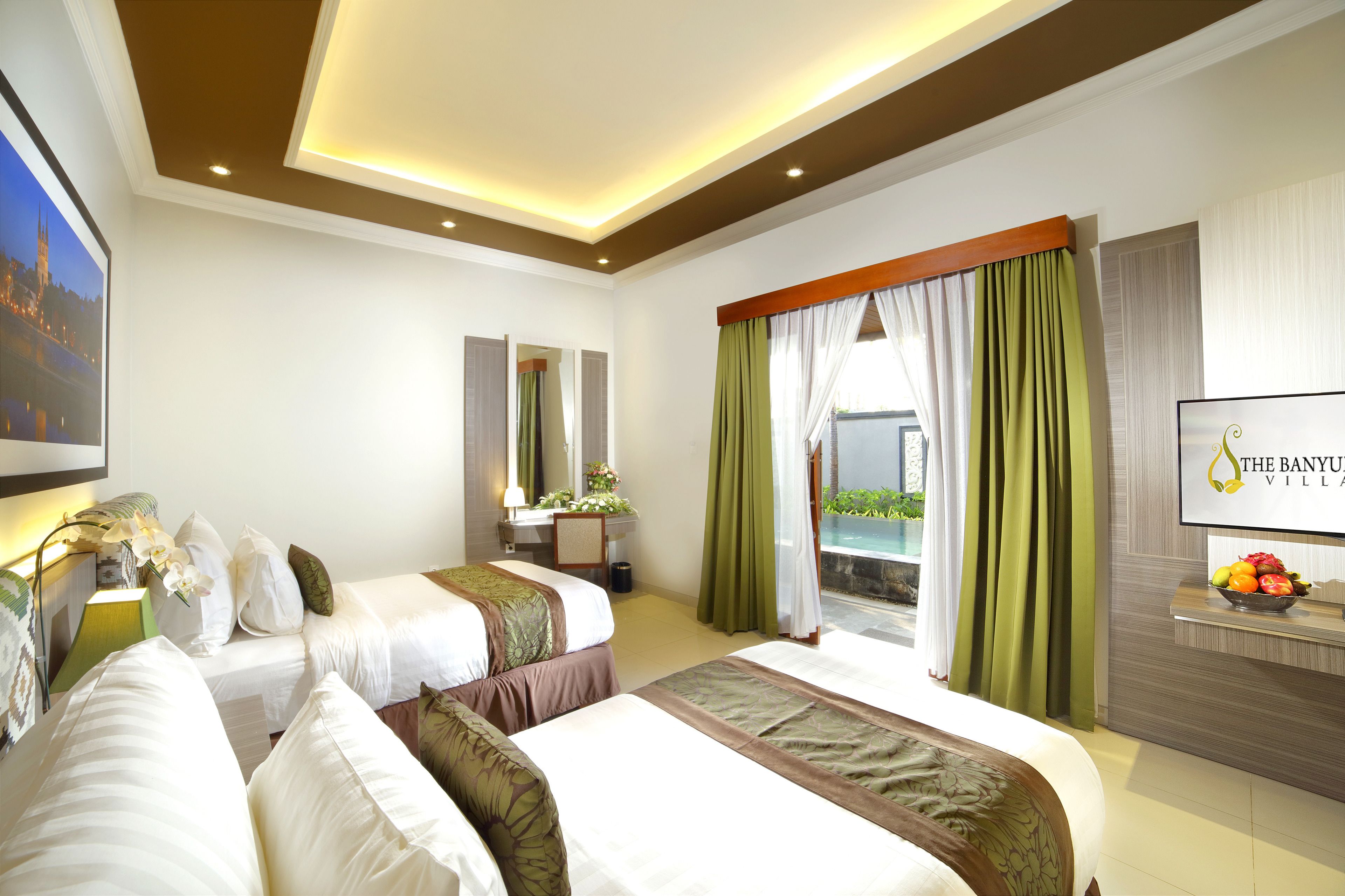 Quarto de hotel com duas camas, uma escrivaninha, televisão e varanda com cortinas.