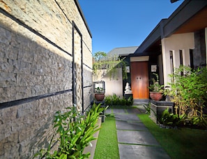 A modern building with a stone facade, a wooden door, and a small garden with a pathway.