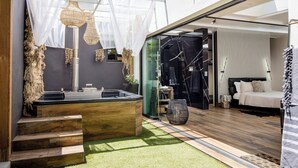 Un bagno esterno moderno con una panchina in legno, una vasca idromassaggio e un’area doccia vetrata.