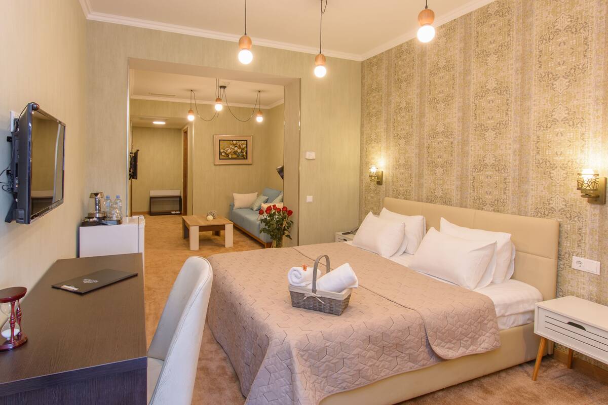 A hotel room with a bed, bedside table, desk, and a chair.