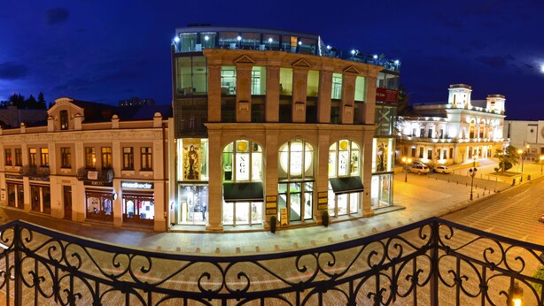 A historic building with a modern glass extension, surrounded by classic architecture. - Hotel King David (Tbilisi)