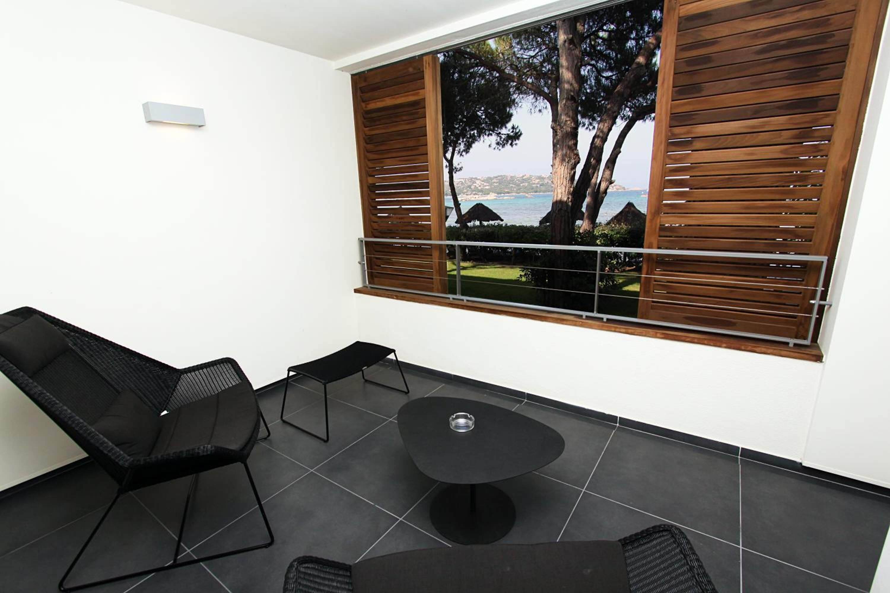 Un espacio moderno al aire libre con vistas al mar, una mesa y dos sillones de descanso.
