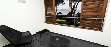 Un espacio moderno al aire libre con vistas al mar, una mesa y dos sillones de descanso.