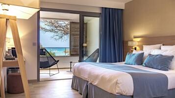 Een moderne hotelkamer met een groot bed, een bureau en uitzicht op zee.