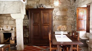 Un comedor rústico con pared de piedra, mesa de madera, sillas y chimenea.