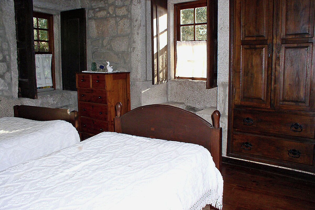 Ein Zimmer mit zwei Holzbett, einem Schminktisch und einem großen Holzschrank.